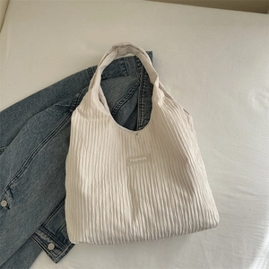 Detail der cremeweißen Tragetasche aus Faltenstoff mit minimalistischem FASHION-Label