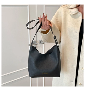 Detail of black lychee grain leather handbag with gold embossed logo and fine hardware