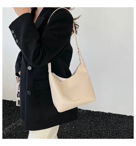 Detail of hobo bag in off-white lychee leather texture with gold logo and thin strap