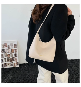 Close-up of beige lychee texture leather shoulder bag with gold logo and sleek Hobo design