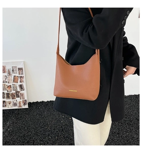 Detailed shot of brown litchi pattern leather bag with golden fashion letter logo