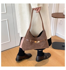 Detail of a brown suede hobo bag featuring a gold buckle and adjustable strap design
