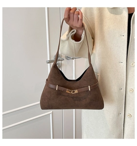 Detail of dark brown suede tote bag featuring a decorative gold buckle and leather strap