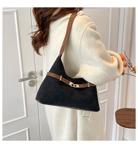 Detail of black suede tote bag with brown leather strap and gold buckle closure