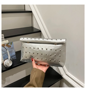 Close-up of silver metallic clutch bag with four rows of silver rivet studs on the flap