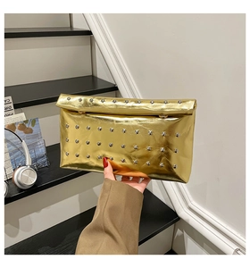 Detail of golden metallic clutch bag with silver studs on a modern stair background
