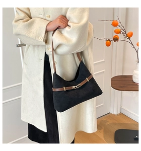 Detailed close-up of a black faux suede tote bag with brown leather strap and metal buckle