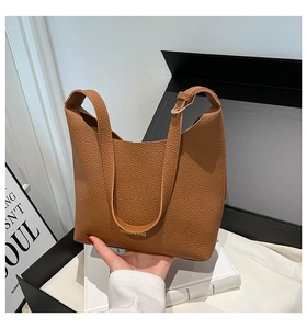 Close-up of brown litchi pattern leather tote with golden FASHION & BAGS logo detail