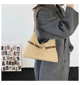 Close-up of beige suede hobo bag with brown leather strap and gold buckle detail