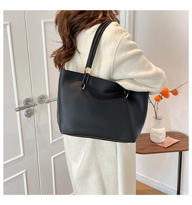 Gros plan d'un sac cabas minimaliste en cuir noir avec détails dorés sur un mannequin