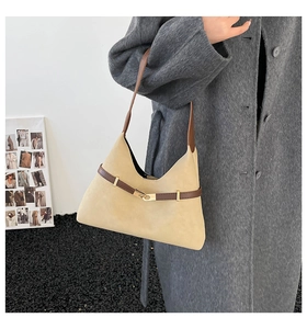 Detailed texture of beige suede tote bag with brown leather straps and gold buckle