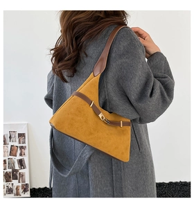 Detail of suede shoulder bag featuring gold buckle and textured leather strap