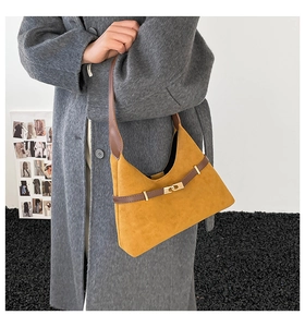 Detail of yellow faux suede tote bag with brown leather strap and gold buckle on grey coat