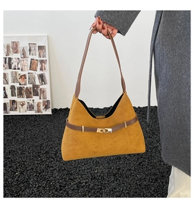 Detail of suede tote bag with interlocking gold metal buckle and brown leather strap