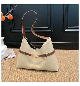 Detail shot of beige suede tote bag with brown strap and golden metal buckle decor