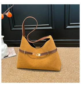 Detailed macro view of yellow suede tote bag featuring brown leather strap and gold buckle