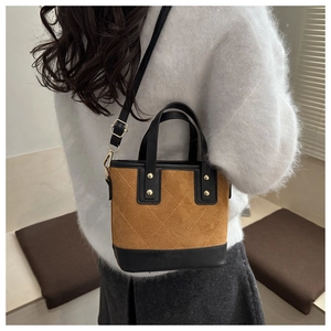 Détail du sac seau matelassé en daim marron et cuir noir porté par le mannequin