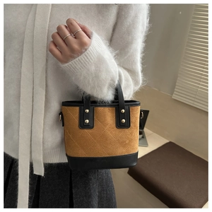 Détail du sac seau matelassé avec rivets dorés et bordure contrastée en cuir noir