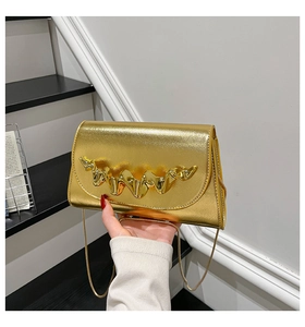 Detail of gold evening clutch with wavy lava texture metal clasp and chain strap