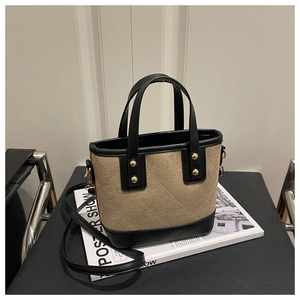 Détail du sac seau matelassé beige avec bordures en cuir noir et rivets dorés