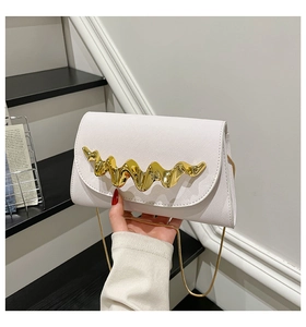 Detail van witte lederen crossbodytas met gouden golfgesp en een elegante gouden kettingriem