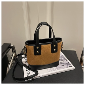 Détail d'un sac seau en daim marron avec bordures en cuir noir et rivets dorés