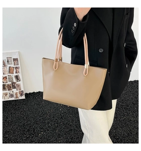Détails d'un sac cabas en cuir beige avec de longues anses et des finitions dorées