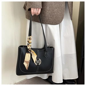 Detail van zwarte tote bag met witte contraststiksels en een decoratieve zijden sjaal