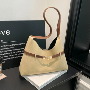 Chic beige suede tote bag with brown leather straps displayed on a white book base