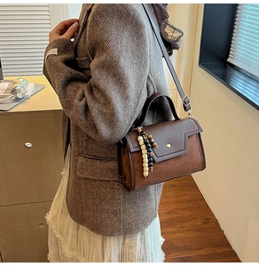 Detail of vintage brown baguette bag with colorful wooden bead tassel and crossbody strap