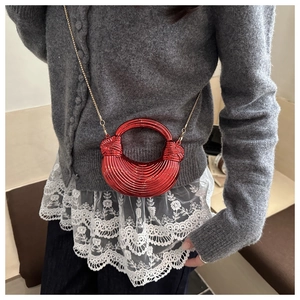 Dettaglio di una borsa a conchiglia in acrilico rosso con texture a righe e catena