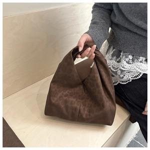 Detail view of brown leopard print knot tote bag in soft suede fabric on wood