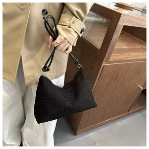 Dettaglio della trama a grata goffrata sulla borsa tote nera con tracolla in pelle