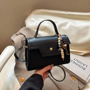 Structured black leather baguette bag with retro wooden beads and a gold magnetic clasp