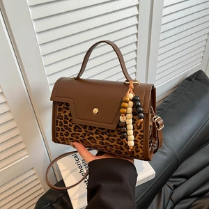 Retro leopard print baguette bag with brown leather and gold clasp shown in hand