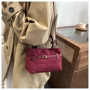 Detail of burgundy suede satchel with belt buckle decoration and crossbody strap