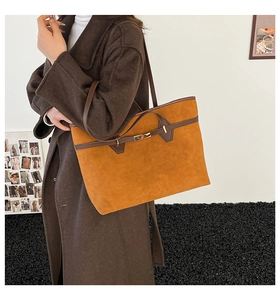 Close-up of caramel suede tote bag with brown leather trim and golden buckle detail