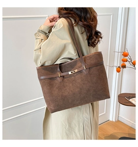Detail of deep brown frosted leather tote bag featuring gold buckle and leather strap
