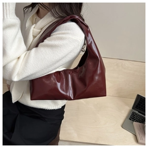 Detail of burgundy patent leather hobo bag showing mirror-like shine and sleek hobo silhouette