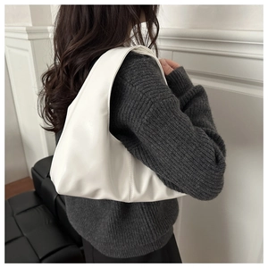 Close-up of white leather hobo shoulder bag worn with a grey knit sweater