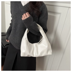 Close-up of white glossy hobo bag with pleated design worn by a model on shoulder
