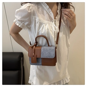 Detail of color-block handbag showing brown leather texture and decorative tag