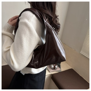 Detail of dark brown glossy leather hobo bag showing premium shiny texture on shoulder