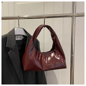 Detail of burgundy patent leather tote bag showing reflective glossy finish and hobo design