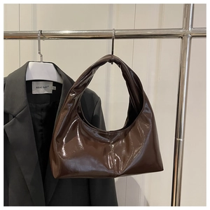 Detailed close-up of glossy caramel brown hobo bag with a shiny patent leather finish