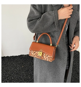 Detail of a brown leather crossbody bag with leopard print and a golden metal lock closure