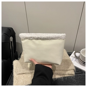 Close-up of off-white faux leather handbag with soft white fleece trim and egg logo tag
