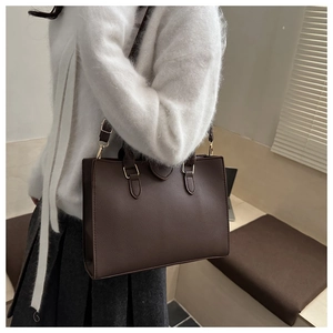 Detail of dark brown lychee texture tote bag with gold metallic buckle for daily wear