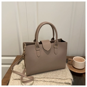 Detail view of taupe lychee texture leather handbag with elegant gold hardware