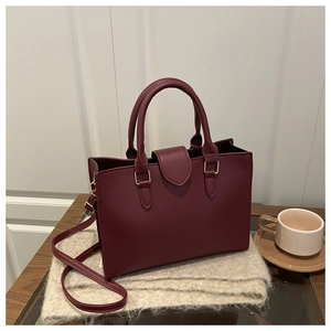 Close-up of burgundy pebble leather handbag with gold hardware on soft scarf